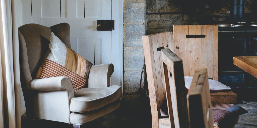 gray wing chair with throw pillows beside white door